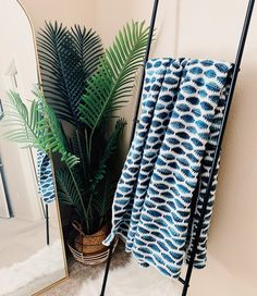 a blue and white towel sitting on top of a metal rack next to a potted plant