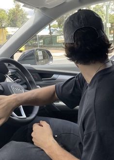 a man sitting in the driver's seat of a car with his hands on the steering wheel