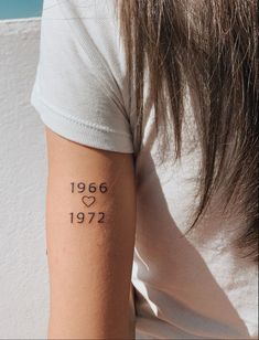 a woman with a tattoo on her arm that reads 1956 and has hearts in it