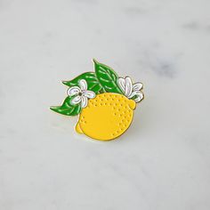 A Hester & Cook Lemon Enamel Pin adorned with leaves. Yellow Enamel Brooches For Gifts, Fresh Fruits, Enamel Pin, Gold Finish, Great Gifts, Enamel Pins, Lemon, Gifts, Gold