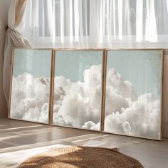 three paintings are hanging on the wall in front of a window with white clouds and sun shining through them