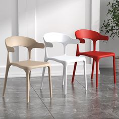 three different colored chairs sitting next to each other on a tile floor near a potted plant