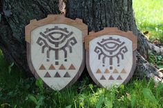 two wooden signs sitting in the grass next to a tree with an eye on it