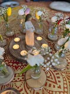 a table topped with vases filled with flowers and candles