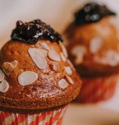 two muffins with blueberries and almonds on top are sitting next to each other