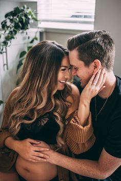 a man and woman cuddle together in their living room