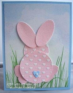 a card with an image of a bunny in the grass and hearts on it's chest