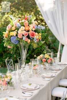 a table set with flowers and plates for an outdoor wedding reception in the sunlit garden