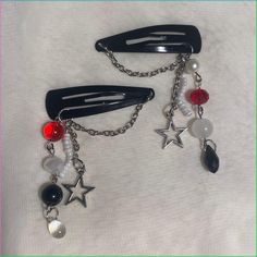 two black hair clips with red, white and black beads hanging from them on a chain