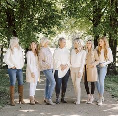 a group of women standing next to each other in front of some trees and grass