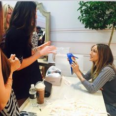 two women sitting at a table and one is holding something in her hand while the other woman looks on