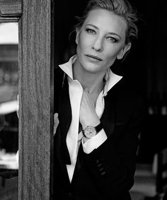 black and white photograph of a woman leaning up against a wooden sign with her hand on her chin