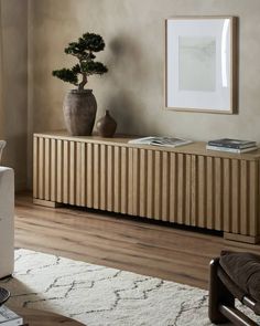 a living room with a large wooden cabinet and potted plant on the sideboard