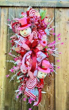 a wreath with candy and candies hanging on a wooden fence, decorated with ribbons