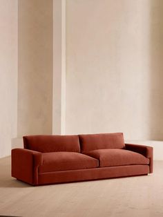 an orange couch sitting on top of a hard wood floor next to a white wall