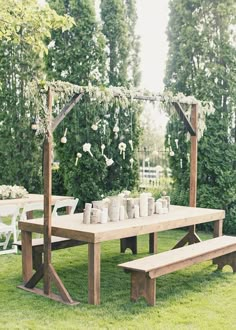 a picnic table with white flowers and greenery on the arbor is set up for an outdoor wedding