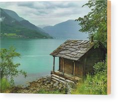 an old cabin sits on the shore of a lake