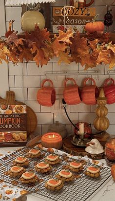 pumpkin themed cookies on a cooling rack with fall leaves hanging from the ceiling above them