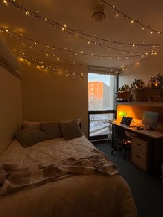 a bedroom with a bed, desk and computer on the wall next to a window