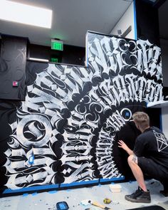 a man is working on an art piece in the process of being painted with black and white paint