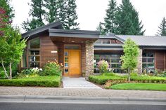 a house that has some plants in front of it and flowers on the ground outside