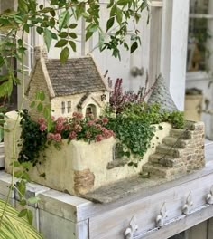 a small house with plants growing out of it's roof and on top of a table