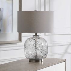 a glass table lamp on top of a dresser