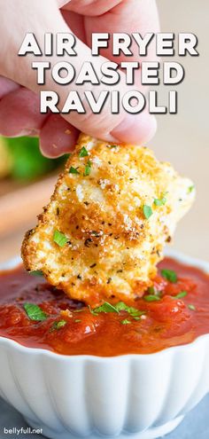 a hand dipping some food into a bowl with sauce and parmesan cheese on top