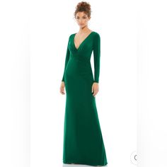 a woman in a long green dress is standing on a white background with her hands behind her back