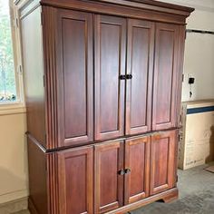 a large wooden cabinet sitting in the middle of a room with carpeted flooring