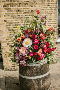 a wooden barrel filled with lots of colorful flowers