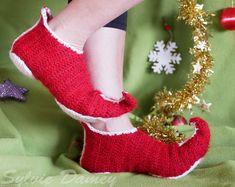 a woman's feet wearing red slippers with snowflakes and christmas decorations