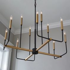 a chandelier with six candles hanging from it's arms in a room