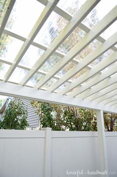 a white pergolated roof with trees in the background