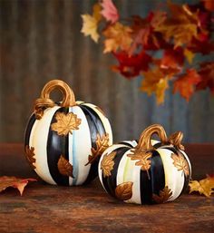 two black and white striped pumpkins sitting next to each other on a wooden table