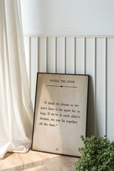 a framed poem sitting on top of a wooden table next to a potted plant