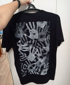 a person holding up a t - shirt with hand prints on it