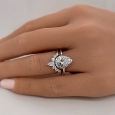 a woman's hand with a diamond ring on top of her finger and an engagement ring in the middle