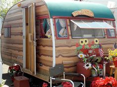 an old camper is decorated with flowers and potted plants