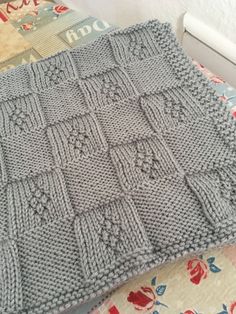 a gray knitted blanket sitting on top of a bed