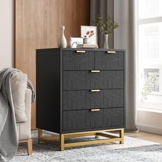 a black and gold chest of drawers in a living room next to a chair with a gray blanket