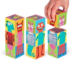 a person is playing with three colorful cubes that look like cartoon characters and monsters