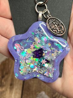 a hand holding a purple keychain with a star design on it