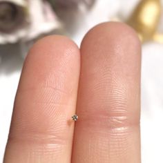 a person's hand with a tiny diamond ring on it