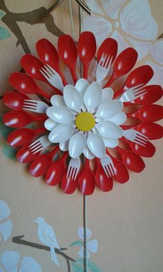 a red and white flower made out of plastic forks