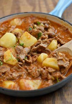 a pot filled with stew and potatoes on top of a wooden table