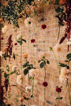 flowers are hanging from the side of a brick wall