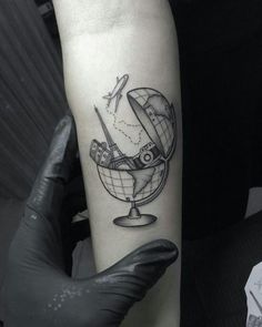 a black and white photo of a globe with an airplane flying over it on the arm