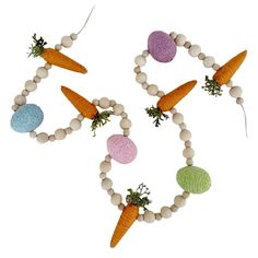 several carrots and eggs are arranged on a beaded necklace that is decorated with wood beads