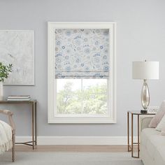 a living room filled with furniture and a large window covered in blue floral roman shades